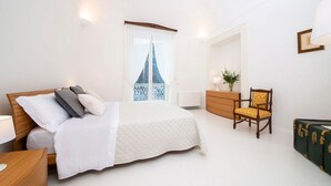 A bedroom with a bed, a wooden nightstand, a dresser, a chair, and a green suitcase. - Villa Del Piano - Four Bedroom Villa, Sleeps 8 (Amalfi)