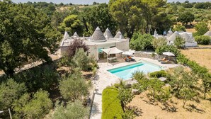 A villa with a swimming pool, surrounded by olive trees and stone structures. - Trulli Daniele - Three Bedroom Villa, Sleeps 6 (Locorotondo)