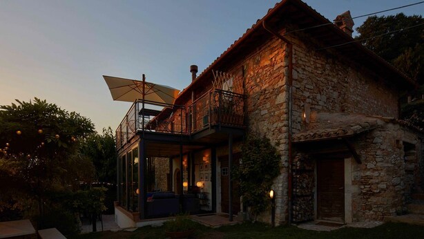 Una casa de piedra con balcón, un porche cubierto y una antena parabólica.