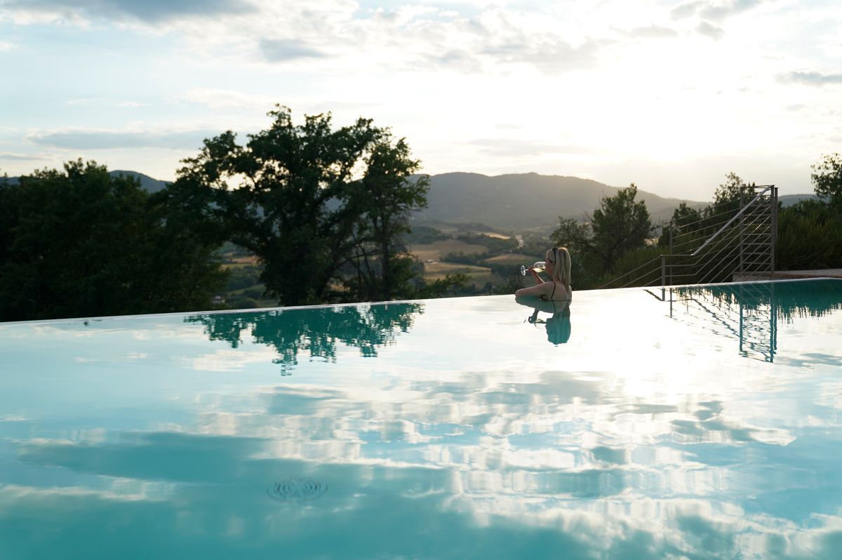 Une piscine aux eaux cristallines, avec en arrière-plan des arbres et des collines.