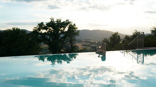 A clear view of a swimming pool with a metal staircase leading down to the water, surrounded by trees and a distant landscape. - I Tebaldi - Eight Bedroom Villa, Sleeps 18 (Reggello)