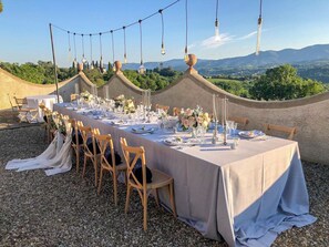 An outdoor dining setup with a table set for multiple guests, surrounded by chairs, and decorated with tableware and flowers. - I Tebaldi - Eight Bedroom Villa, Sleeps 18 (Reggello)