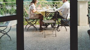 A couple dining at a table with a scenic view of a town and hills in the background. - I Tebaldi - Eight Bedroom Villa, Sleeps 18 (Reggello)