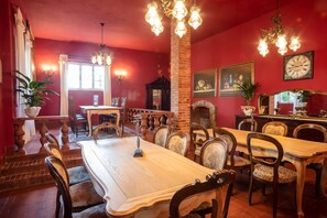 A dining area with a long table, chairs, and a chandelier.