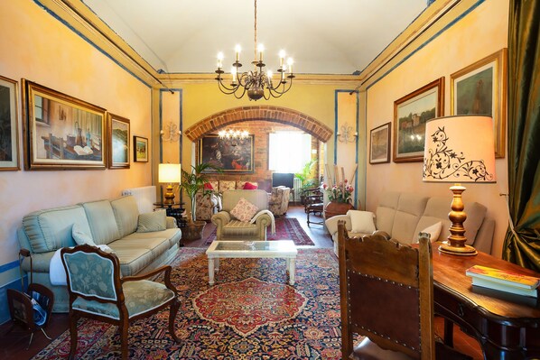 A traditional living room with a chandelier, sofas, armchairs, and a patterned rug.