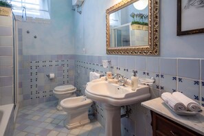 A bathroom with a toilet, bidet, sink, and a mirror.