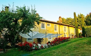 A yellow building with a garden, white tent-like structures, and red flowers.