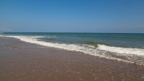 Ein Strand mit sanft anschwellenden Wellen unter einem klaren, blauen Himmel.