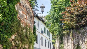 Una calle adoquinada bordeada por muros de piedra y un edificio con tejado de baldosas y contraventanas verdes.