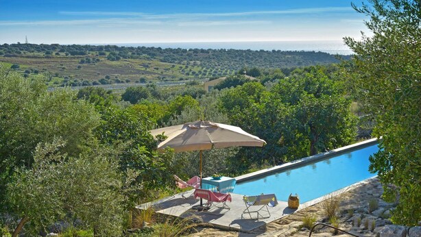 A pool area with a stone wall, lounge chairs, and an umbrella. - La Picca Estate - Six Bedroom Villa, Sleeps 12 (Scicli)