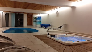 En inomhuspool med bubbelbad och solstolar.