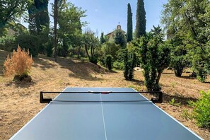 A table tennis table in an outdoor setting with trees and a building in the background.