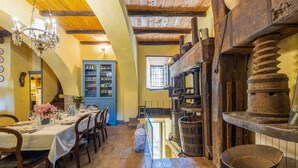 Un comedor con mobiliario de madera, un candelabro y una chimenea de piedra.