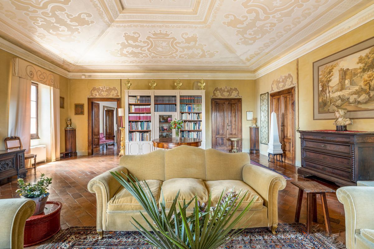 Amplia habitación con un sofá color beige, una estantería grande y un diseño de techo clásico.