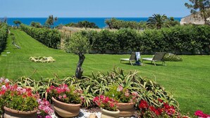 Un jardin bien entretenu, avec une pelouse, des plantes en pot et une vue sur la mer.