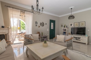 A living room with a sofa, chairs, a coffee table, a TV, and a fireplace.