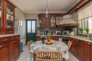 A kitchen with wooden cabinets, a dining table with a fruit bowl, and a microwave.