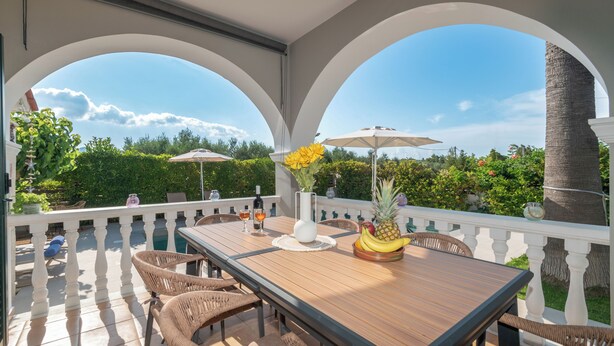 Une terrasse extérieure avec une table en bois, des chaises en osier et des parasols.