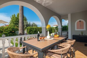 An outdoor patio with a table, chairs, a bottle, and glasses.
