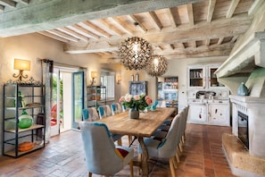 A rustic dining area with a wooden table, chairs, and a decorative chandelier.