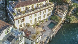 Ein großes, mehrstöckiges Gebäude mit Innenhof, Swimmingpool und einer Anlegestelle, die sich in ein Gewässer erstreckt.