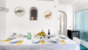 Ein Esszimmer mit einem weißen Tisch, gedeckt für sechs Personen, mit einer Vase gelber Blumen, einer Weinflasche und einem dekorativen Teller mit Giraffendesign.