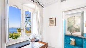 Ein Zimmer mit Meerblick, ein Holztisch mit einer Vase und eine blaue, mit Fliesen versehene Wand.