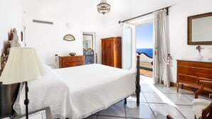 Ein Schlafzimmer mit Bett, Kommode und Meerblick.