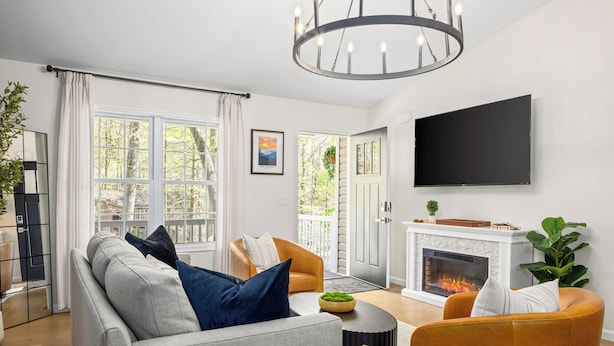 A modern living room with a fireplace, a sofa, a coffee table, and a television mounted on the wall.