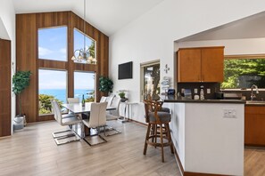 A modern kitchen with wooden cabinetry, a dining area with a view, and a bar area. - Pet-friendly Oceanfront Retreat w/King Beds & Hot Tub! (Gualala)