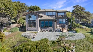 Una casa a due piani con ampie finestre, un terrazzo e un giardino curato.
