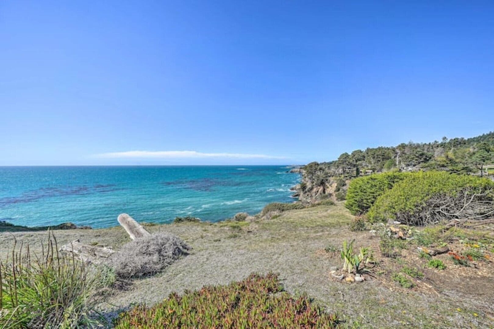 A coastal landscape with a clear view of the sea and rocky terrain.