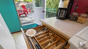 A kitchen with a drawer organizer containing utensils, a coffee maker, and jars on the counter.