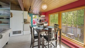 A modern kitchen with a dining area, large windows, and a view of the outdoors.