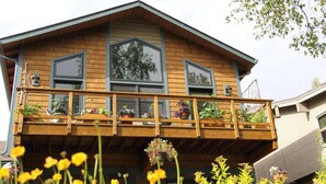 A wooden house with a balcony, large windows, and potted plants. - Historic, Heart of City Home - Near U/Med District (Anchorage)