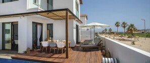 A modern outdoor patio with a dining table, chairs, and lounge area with umbrellas.