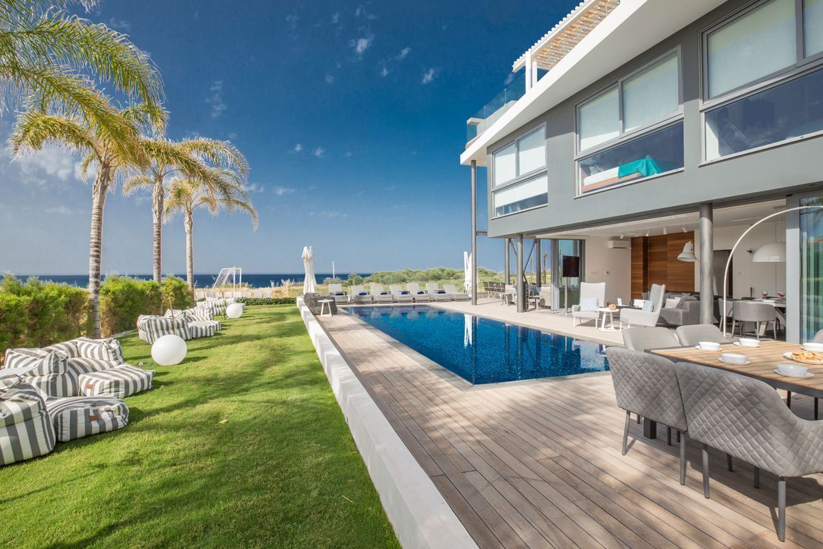 A modern house with a pool, outdoor furniture, and a view of the ocean.