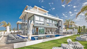A modern two-story house with a swimming pool, outdoor seating, and a well-maintained lawn.
