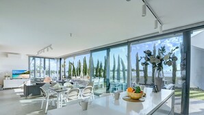 Eine moderne Küche mit großen Fenstern, einem Essbereich und Meerblick.