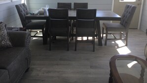 A dining area with a table and six chairs, a sofa, and a glass coffee table.