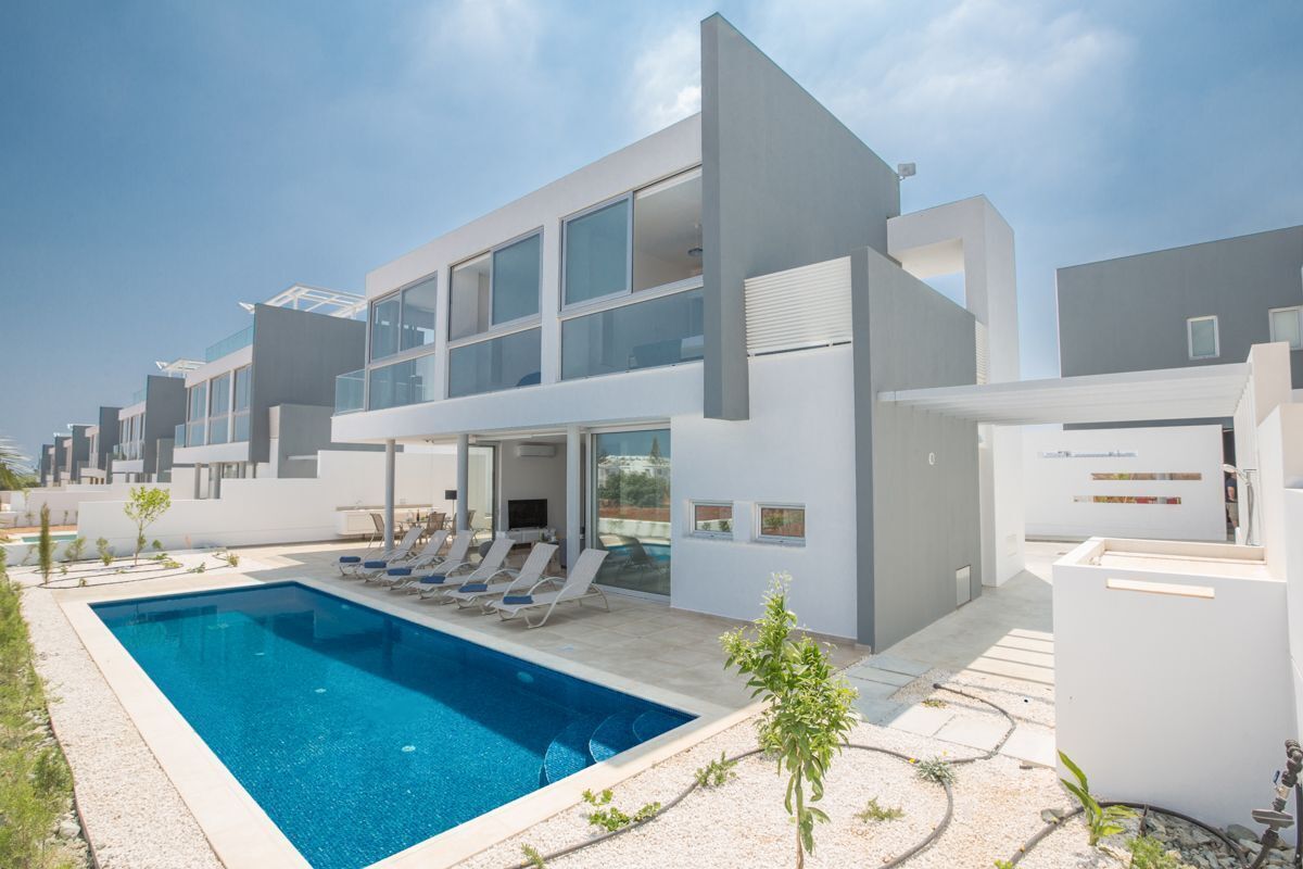 A modern hotel with a swimming pool, lounge chairs, and a clear view of the city skyline.