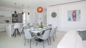 Een moderne keuken met witte kastjes, een roestvrijstalen koelkast en hangende lampen.