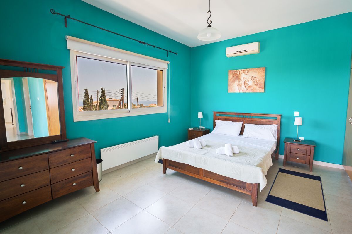 A bedroom with a bed, a dresser, a nightstand, a window, and a radiator.