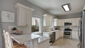 A kitchen with white cabinets, a stainless steel refrigerator, a microwave, and a dishwasher.
