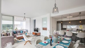 A modern living room with a dining area, large windows, and a kitchen with dark cabinets. - Villa Aglaia - Three Bedroom Villa, Sleeps 8 (Πρωταράς)