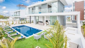A modern two-story house with a swimming pool, outdoor seating, and a well-maintained lawn. - Villa Aglaia - Three Bedroom Villa, Sleeps 8 (Πρωταράς)