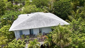 A house with a sloped roof surrounded by lush greenery. - Your Grove Home (Miami)