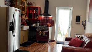 A modern kitchen with a stainless steel refrigerator, red cabinets, and a red stove. - Your Grove Home (Miami)