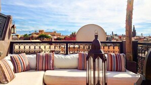A rooftop terrace with a white sofa, striped cushions, and a lantern.