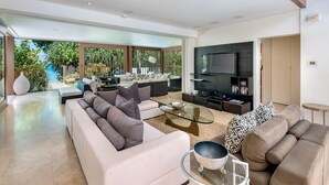 A spacious living room with a large TV, comfortable seating, and a glass coffee table. - Villa Lily Pad - Three Bedroom Villa, Sleeps 6 (Gibbes)